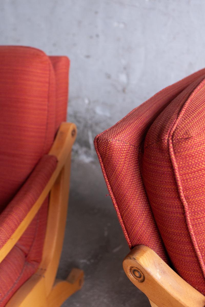 Pair of red fabric and wooden club chairs with soft lined design.