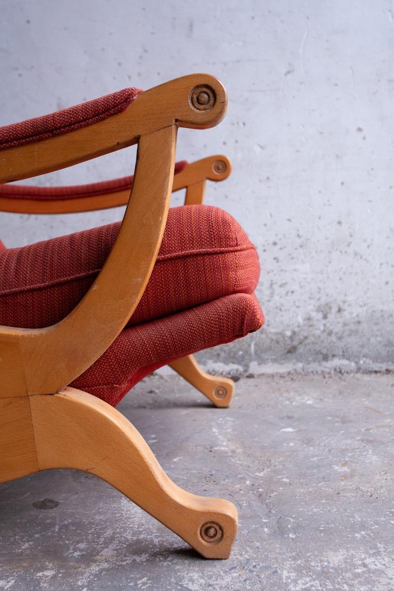 Pair of red fabric and wooden club chairs with soft lined design.