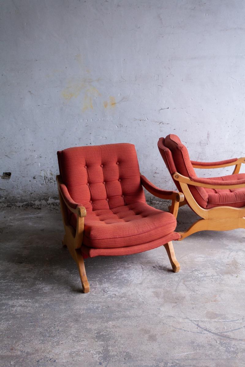 Pair of red fabric and wooden club chairs with soft lined design.